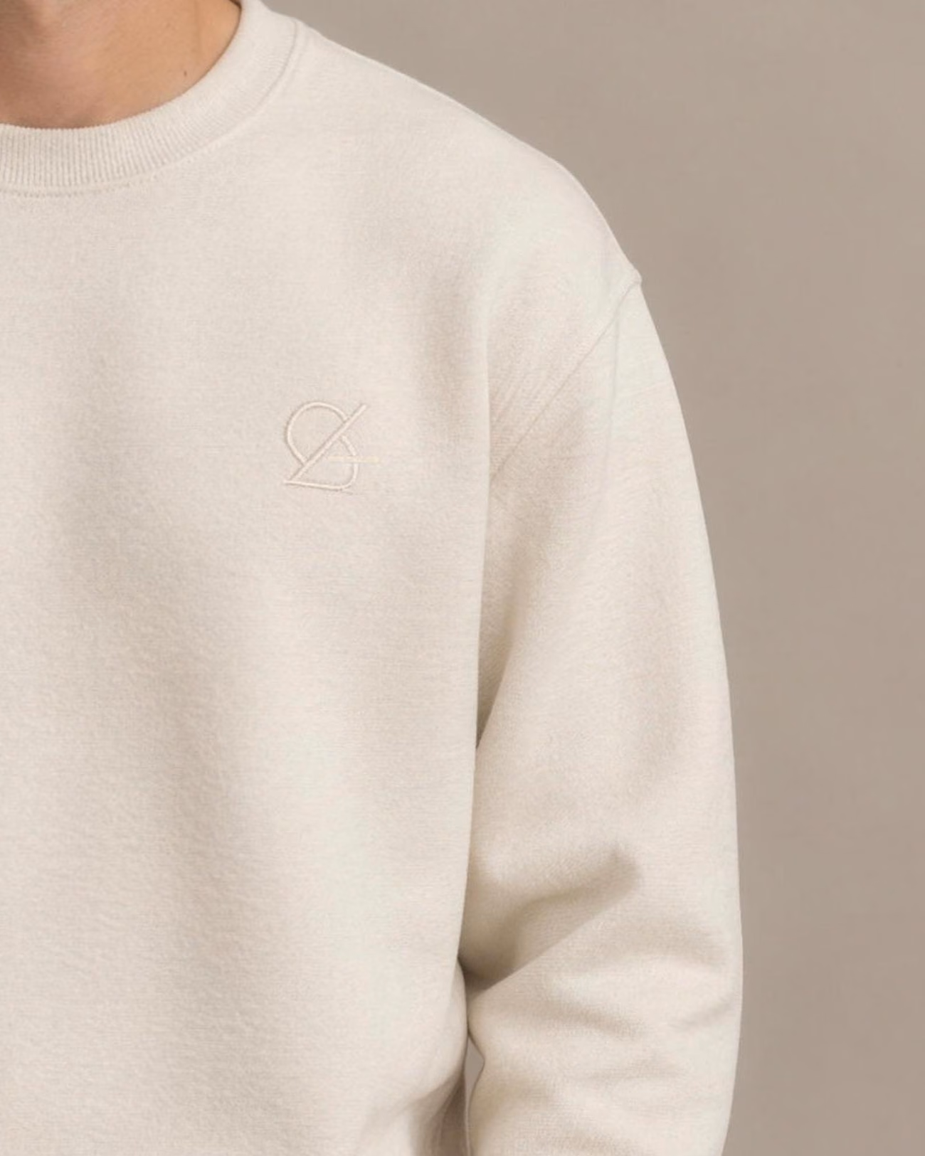 Nahansicht desselben Bildes: Sweatshirt in Creme mit Ton-in-Ton gesticktem Emblem auf der Brust